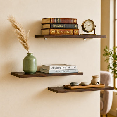 Set of three dark walnut floating wooden wall shelves in a living room
